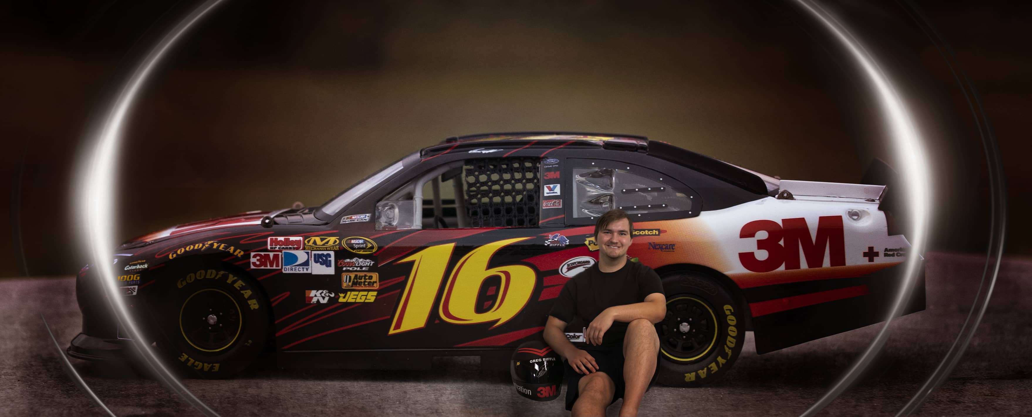 Boy sits next to a race car